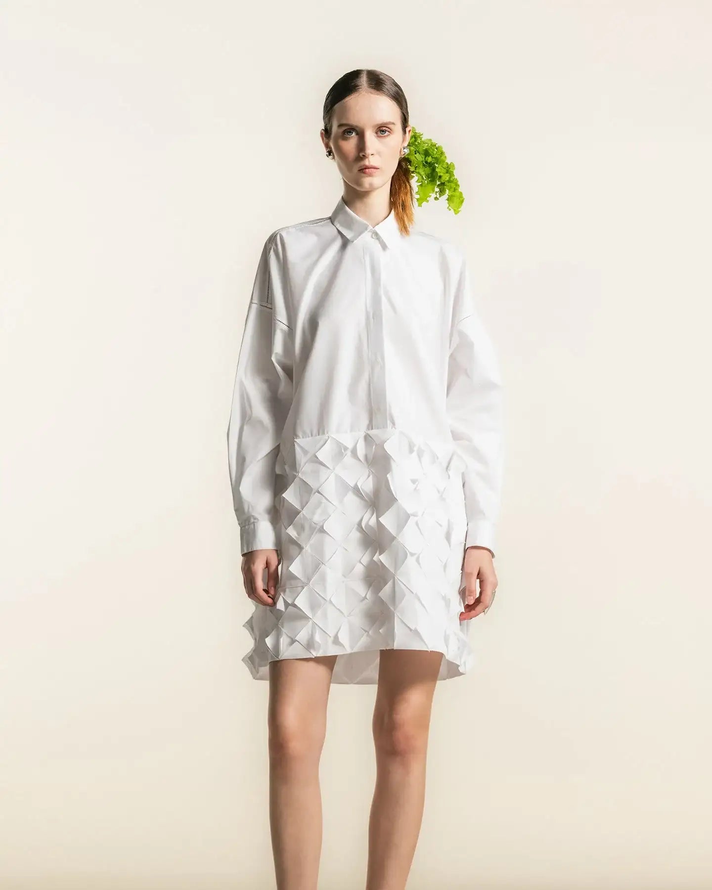 Woman in white shirt dress with textured geometric skirt, minimalist studio background