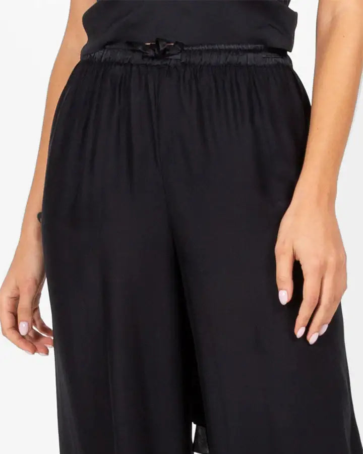 Woman wearing black wide-leg pants with elastic waistband and bow detail