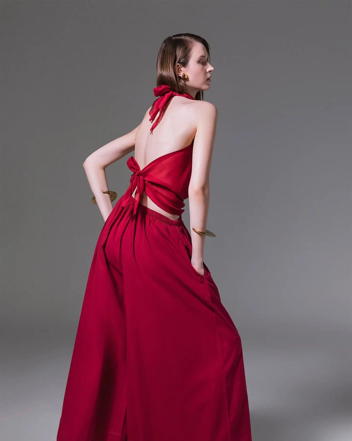 Woman modeling a red backless halter top and wide-leg pants set, modern fashion style