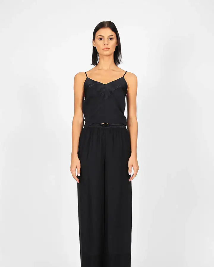 Woman wearing black sleeveless top and wide-leg pants, minimalist fashion look