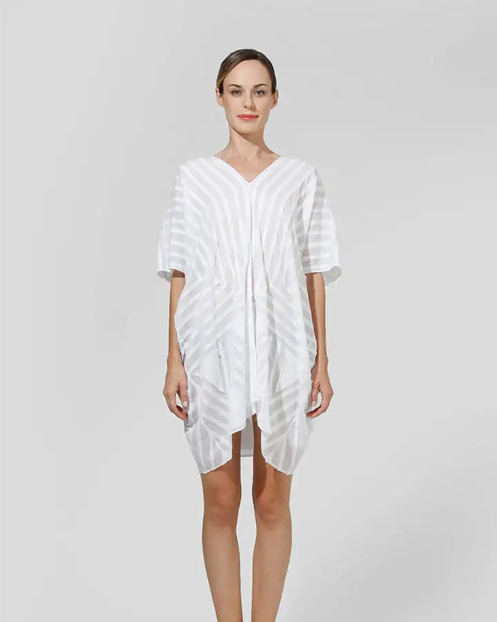 Woman wearing a sheer white striped kaftan dress, minimalist studio background