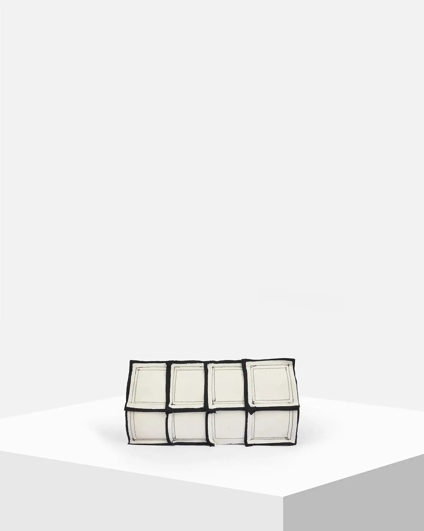 Geometric white and black clutch bag with square pattern on minimalist display