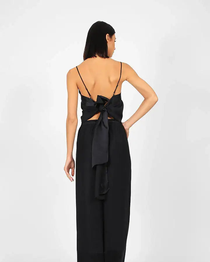 Woman wearing black wide-leg pants and backless top with bow, minimal fashion look