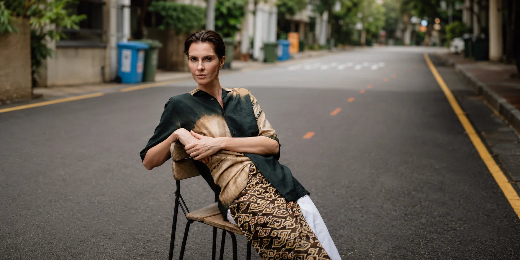 Woman sitting on a chair in the middle of an empty street