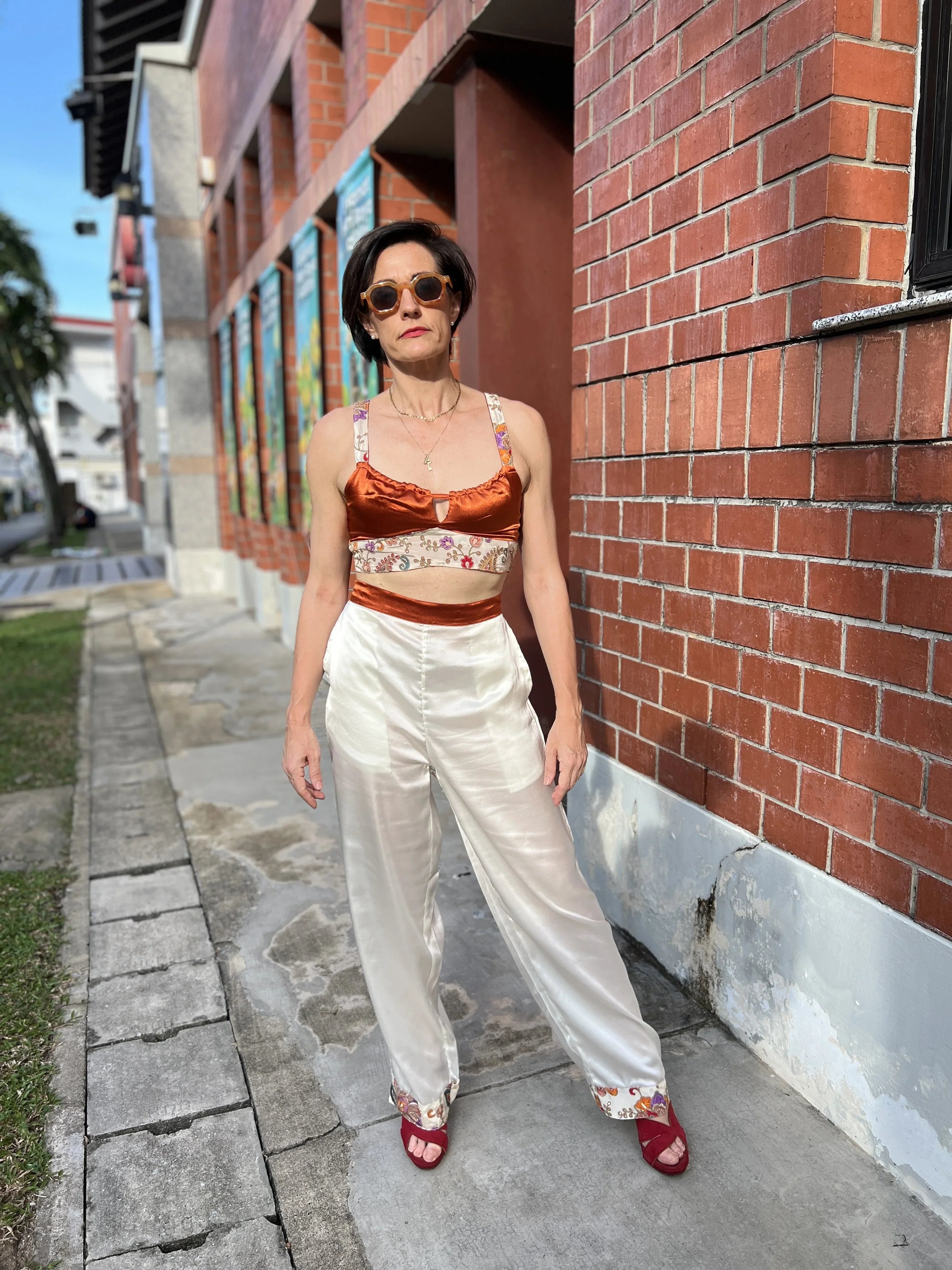 Woman in modern Singapore fashion wearing a satin crop top and wide-leg silk pants outdoors