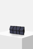 Rectangular blue denim clutch bag with patchwork design on white display pedestal