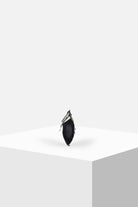 Minimalist black handbag with fringe detailing on white geometric display stand