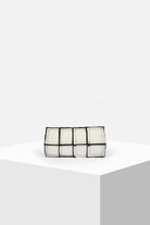 Geometric white and black clutch bag with square pattern on minimalist display
