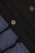 Close-up of blue denim and black fabric with metal snap button details on apparel